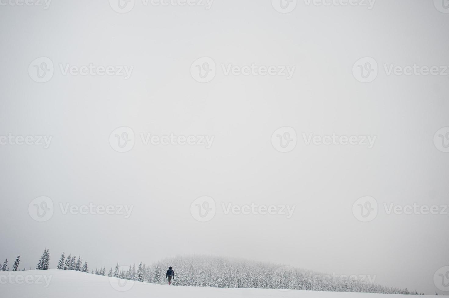 mann touristenfotograf mit rucksack, am berg mit schneebedeckten kiefern. wunderschöne Winterlandschaften. Frost Natur. foto