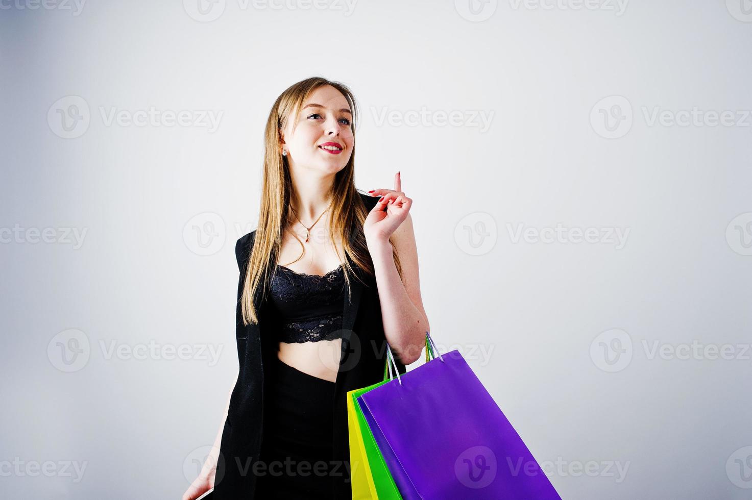 Mädchenmodell in schwarzer Kleidung mit farbigen Einkaufstaschen posierte im Studio auf weißem Hintergrund. foto