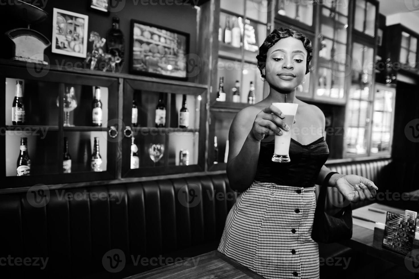 Porträt einer afroamerikanischen Frau, Retro-Frisur, die im Restaurant mit einer Tasse Latte posiert. foto