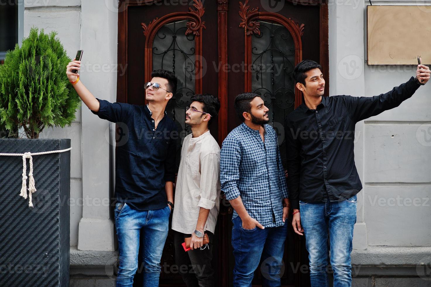 Gruppe von vier indischen Ethnizität Freundschaft Zusammengehörigkeit mans. Technik und Freizeit, Jungs mit Telefonen. Selfies machen. foto