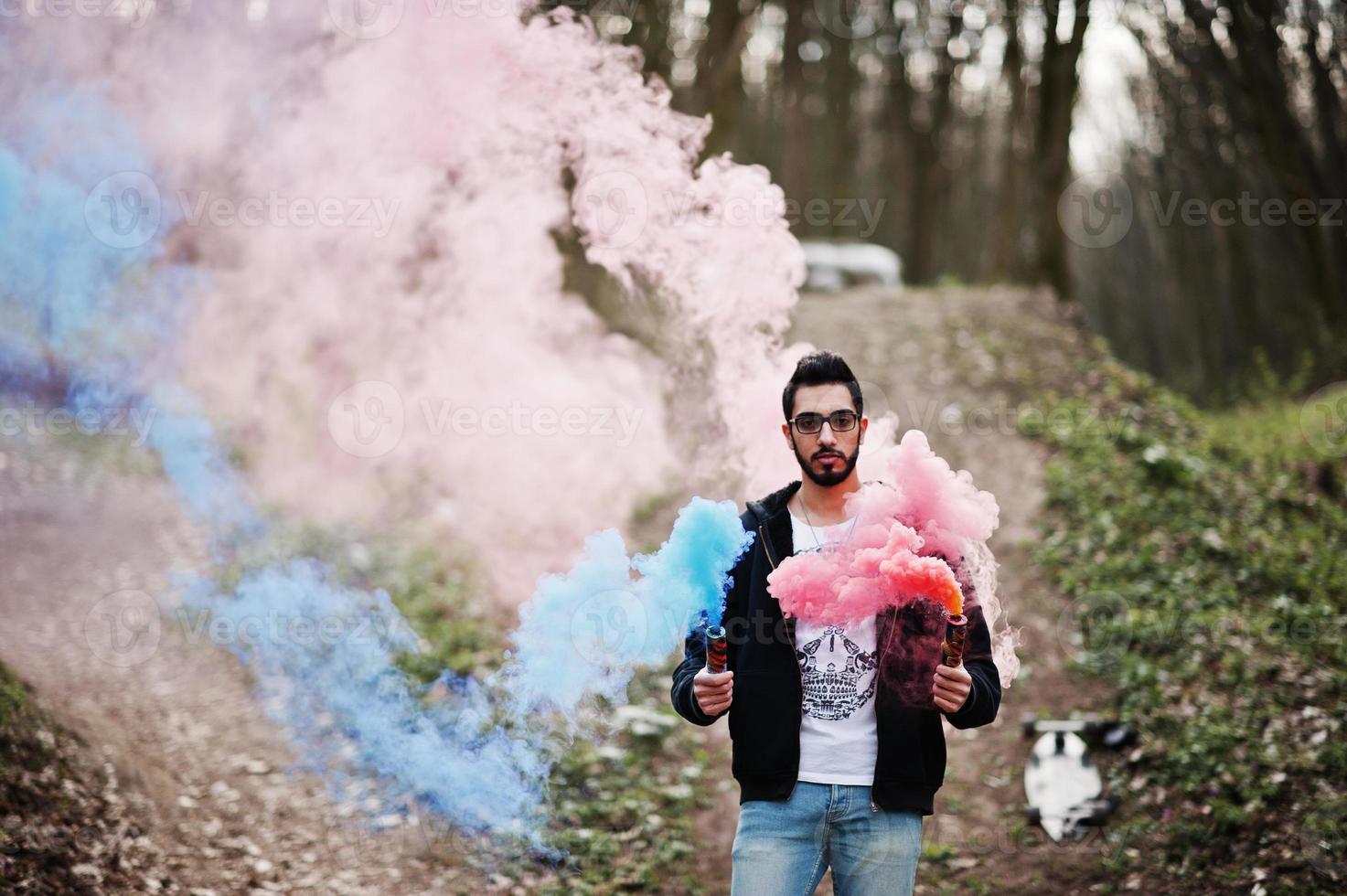 arabischer Streetstyle-Mann mit Brille hält Handfackel mit roter und blauer Rauchgranatenbombe. foto