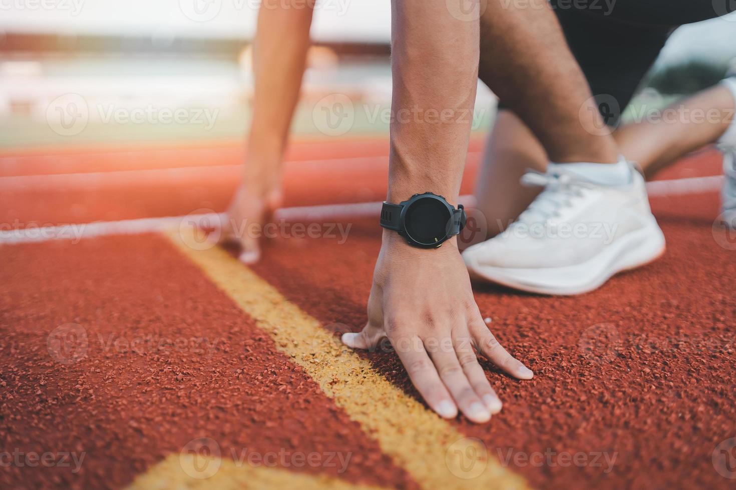 hände läufer startbereit zum runthlete sportman training laufen morgens auf der spur im stadion. läufermann, der weiße weste trägt, um das laufen zu üben, bereite sich auf das wettkampfrennen vor. foto