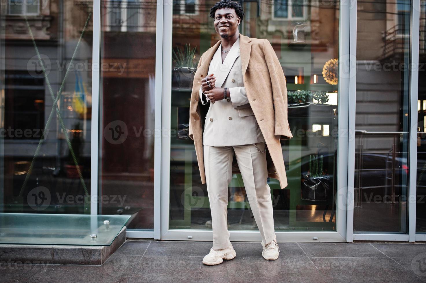 stylischer Afro-Mann in beigem Old-School-Anzug und Mantel. Modischer junger afrikanischer Mann in Freizeitjacke auf nacktem Oberkörper. foto