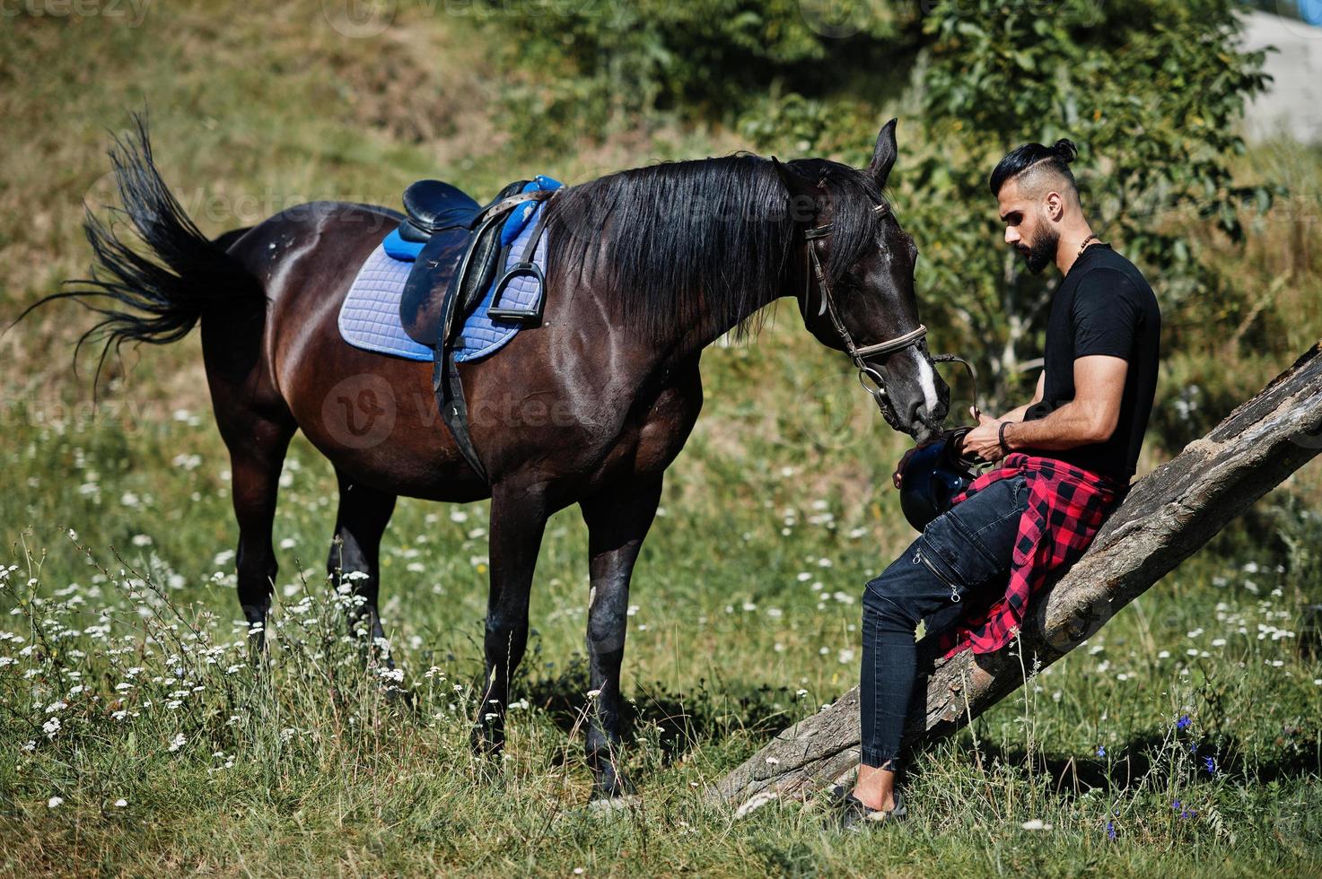 arabischer Mann mit hohem Bart in Schwarz mit arabischem Pferd. foto