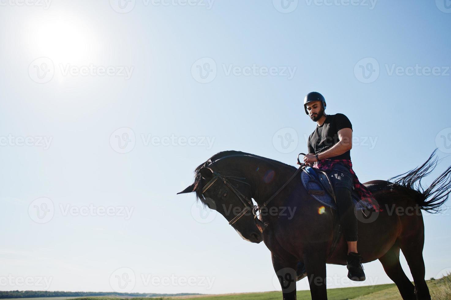 arabischer großer bartmann trägt schwarzen helm, reitet arabisches pferd. foto