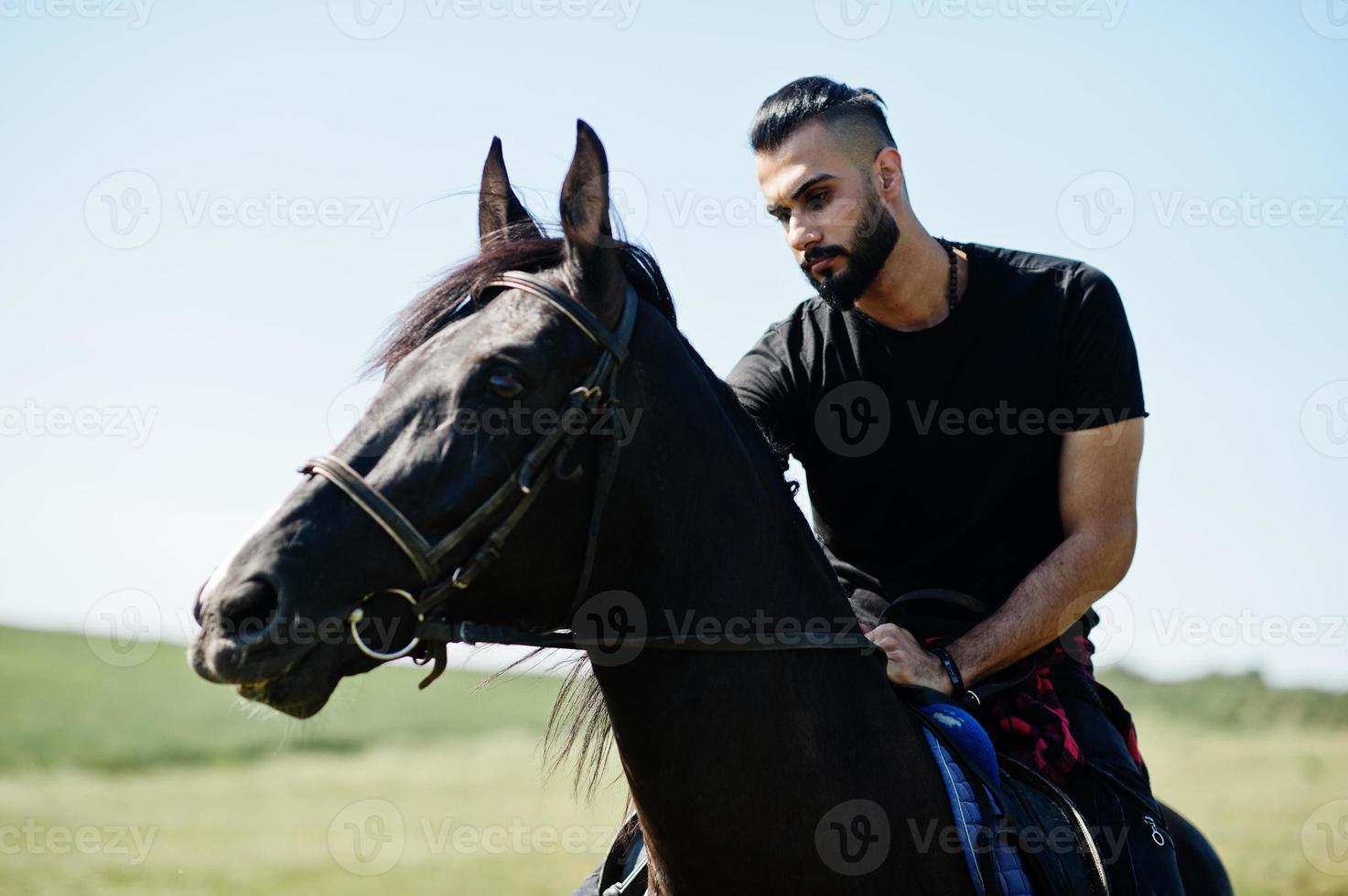 arabischer Mann mit hohem Bart trägt schwarzes arabisches Pferd. foto