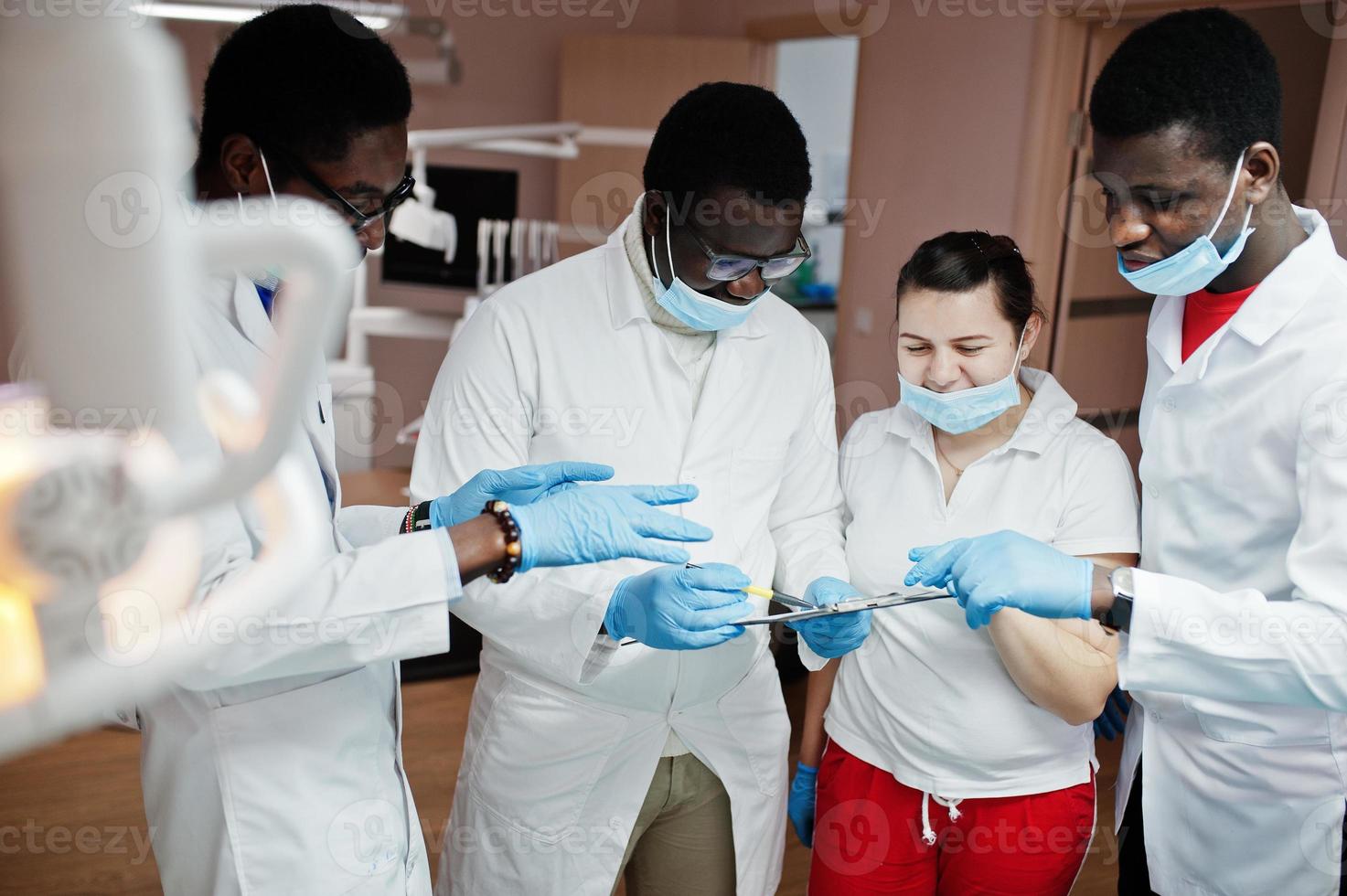 gemischtrassiges zahnarztteam. drei afroamerikanische männliche ärzte mit einer kaukasischen ärztin. Besprechung von Arbeitsmomenten. foto