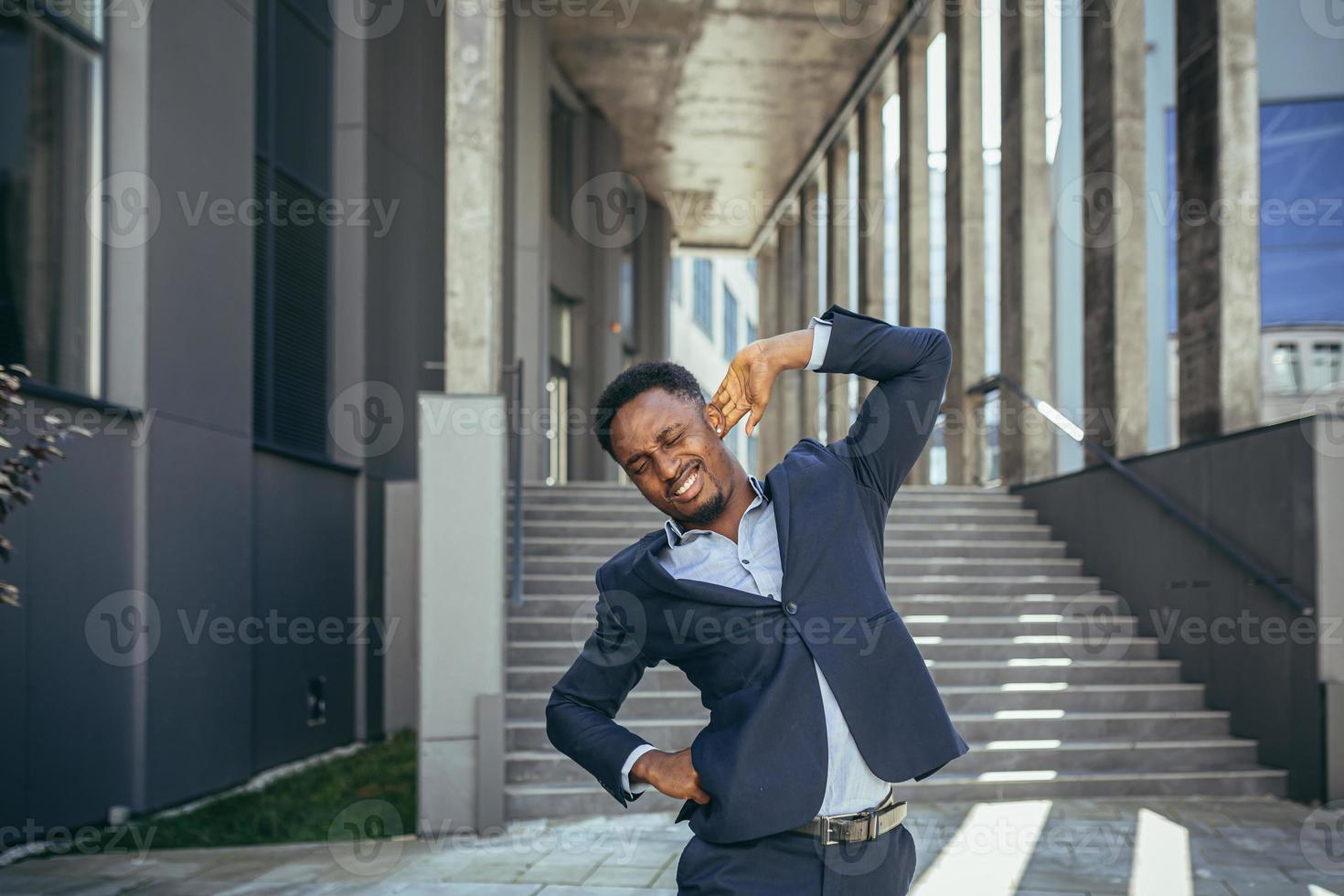 geschäftsmann hat starke rückenschmerzen bei der arbeit, afroamerikanischer freiberufler in der nähe des büros foto