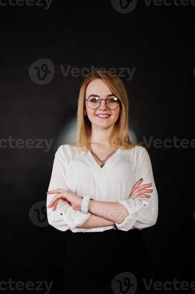 Studioporträt einer blonden Geschäftsfrau mit Brille, weißer Bluse und schwarzem Rock vor dunklem Hintergrund. erfolgreiche frau und stilvolles mädchenkonzept. foto