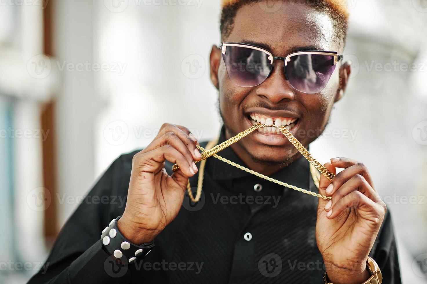 schicker, gut aussehender afroamerikanischer mann in schwarzem hemd mit goldener kette und sonnenbrille. foto