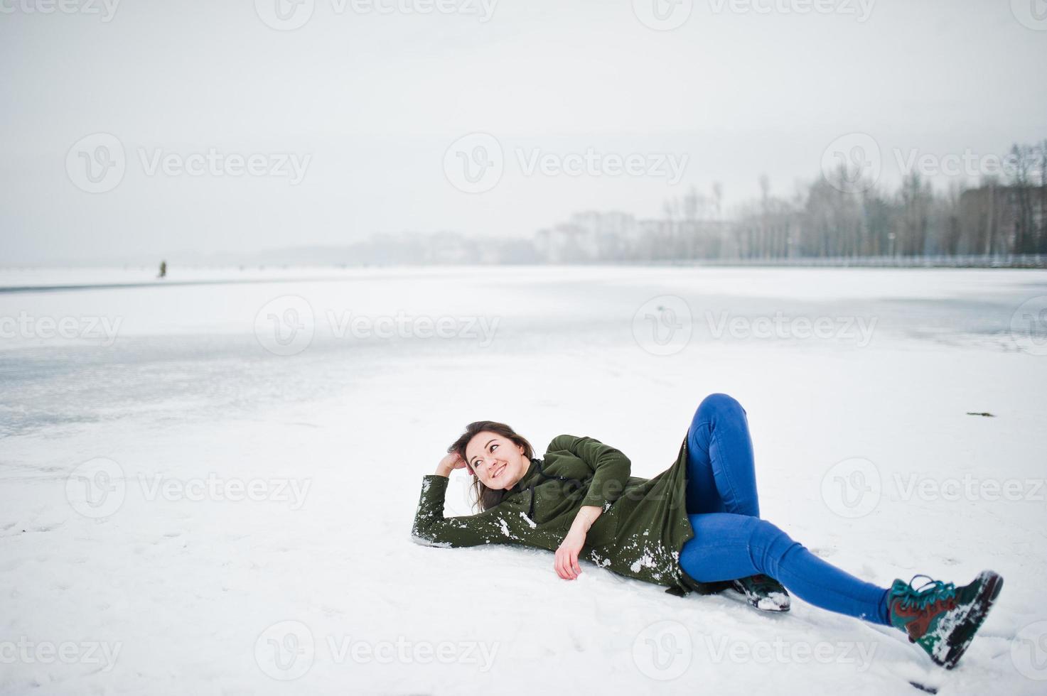 Lustige Mädchen tragen lange grüne Sweatshirts und Jeans, am zugefrorenen See im Wintertag. foto