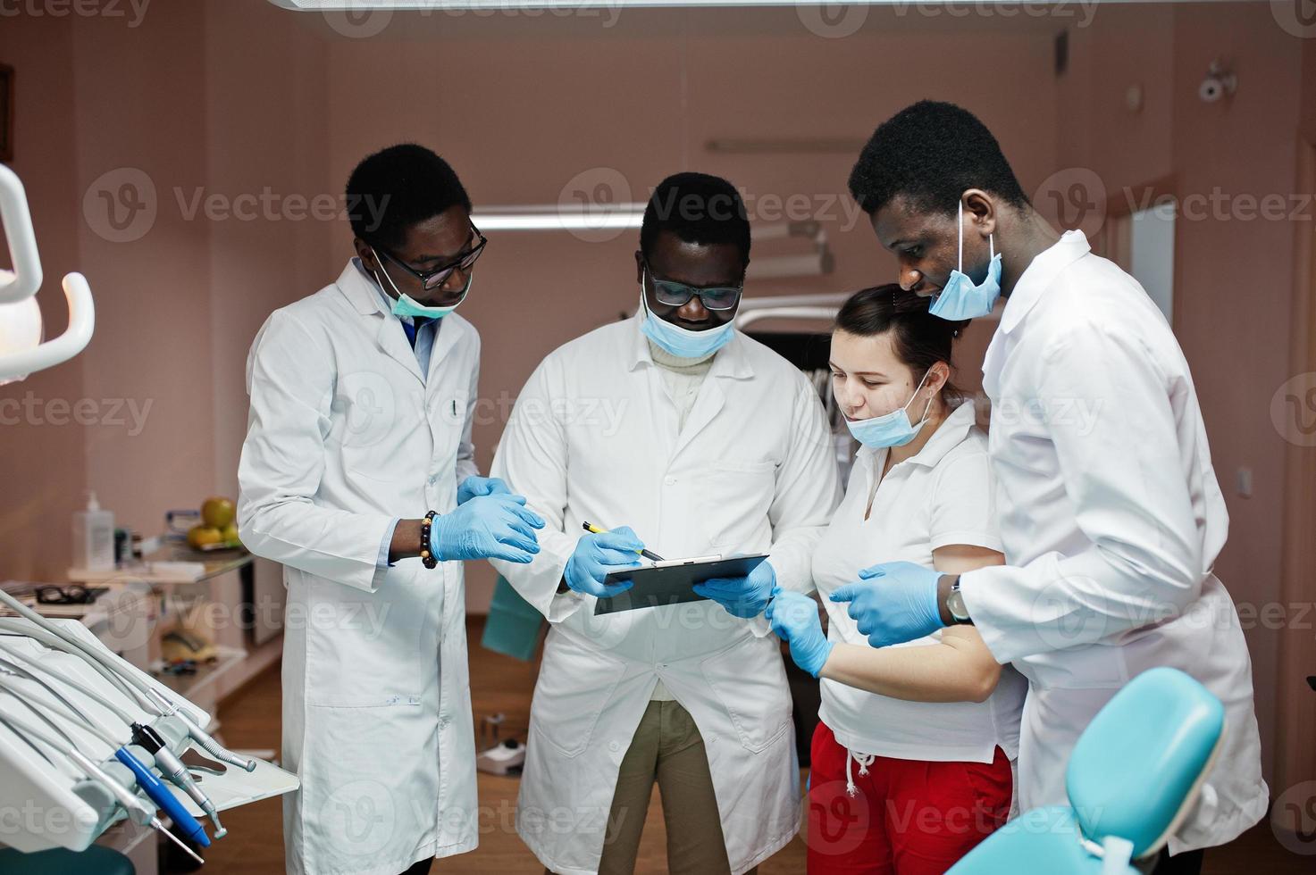 gemischtrassiges zahnarztteam. drei afroamerikanische männliche ärzte mit einer kaukasischen ärztin. Besprechung von Arbeitsmomenten. foto