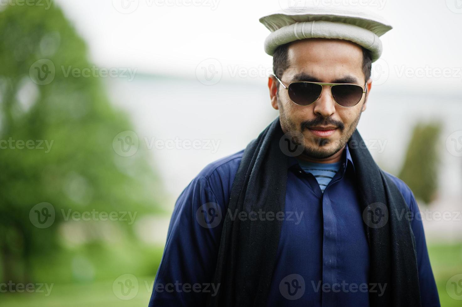 Stilvoller pakistanischer indischer muslimischer arabischer Mann in Kurta-Dhoti-Anzug, traditionellem Pakol-Hut und Sonnenbrille. foto