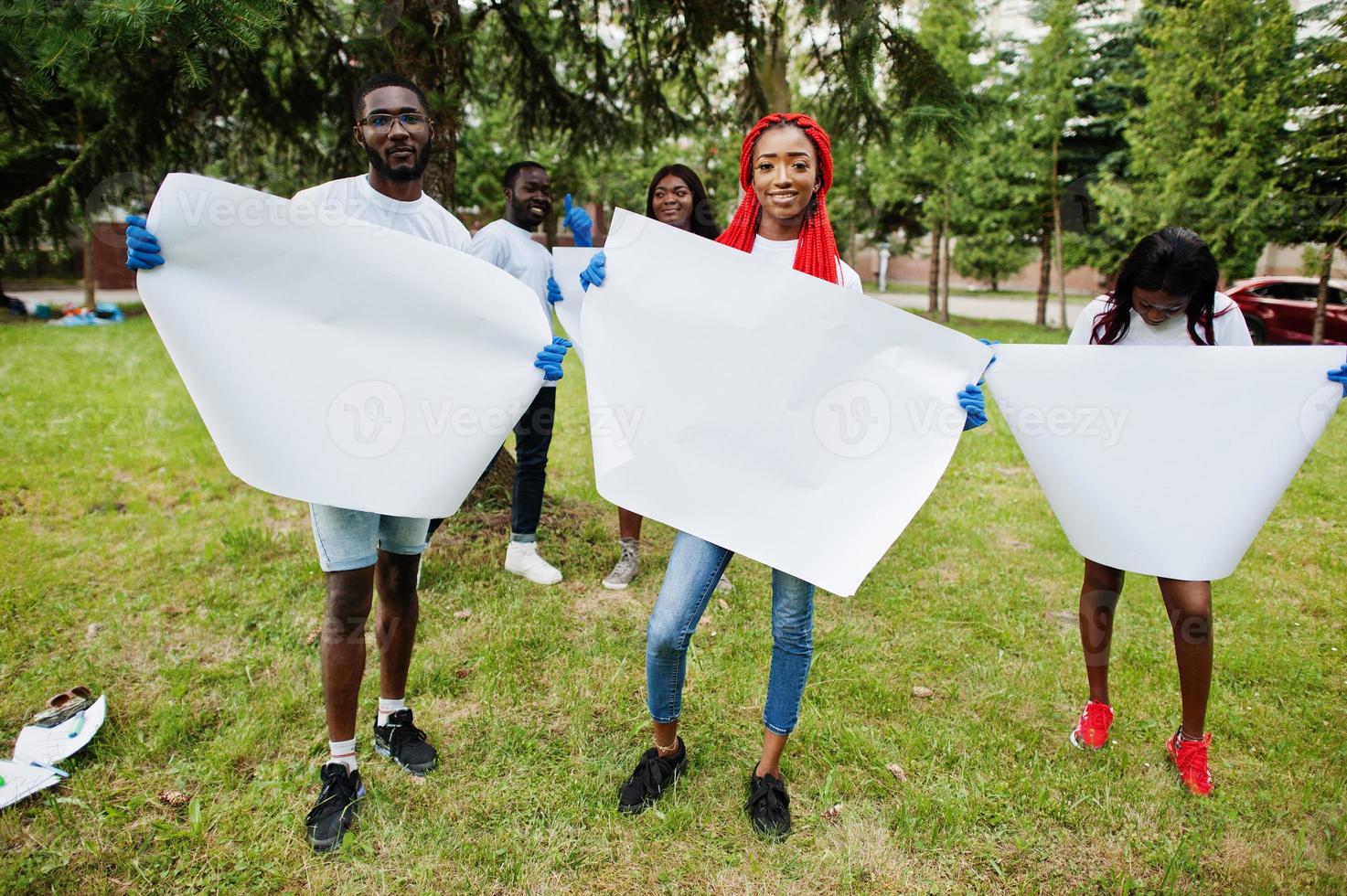 eine gruppe glücklicher afrikanischer freiwilliger hält ein leeres leeres brett im park. afrika-freiwilligenarbeit, wohltätigkeit, menschen und ökologiekonzept. Freiraum für Ihren Text. foto