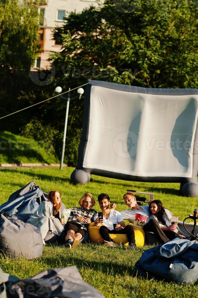 junge multiethnische gruppe von menschen, die filme im poof im open-air-kino ansehen. foto