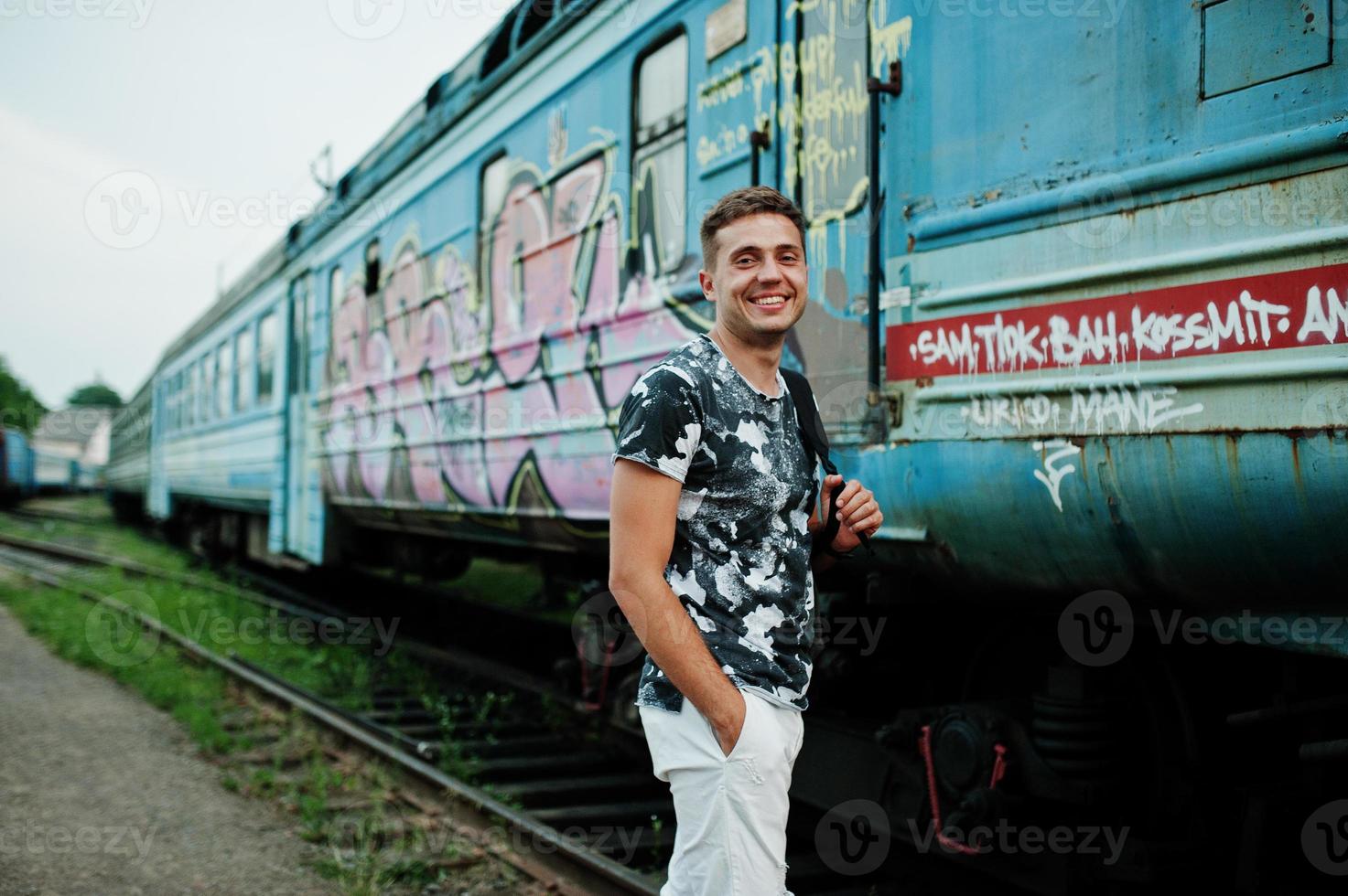 Lifestyle-Porträt eines gutaussehenden Mannes mit Rucksack, der auf dem Bahnhof posiert. foto