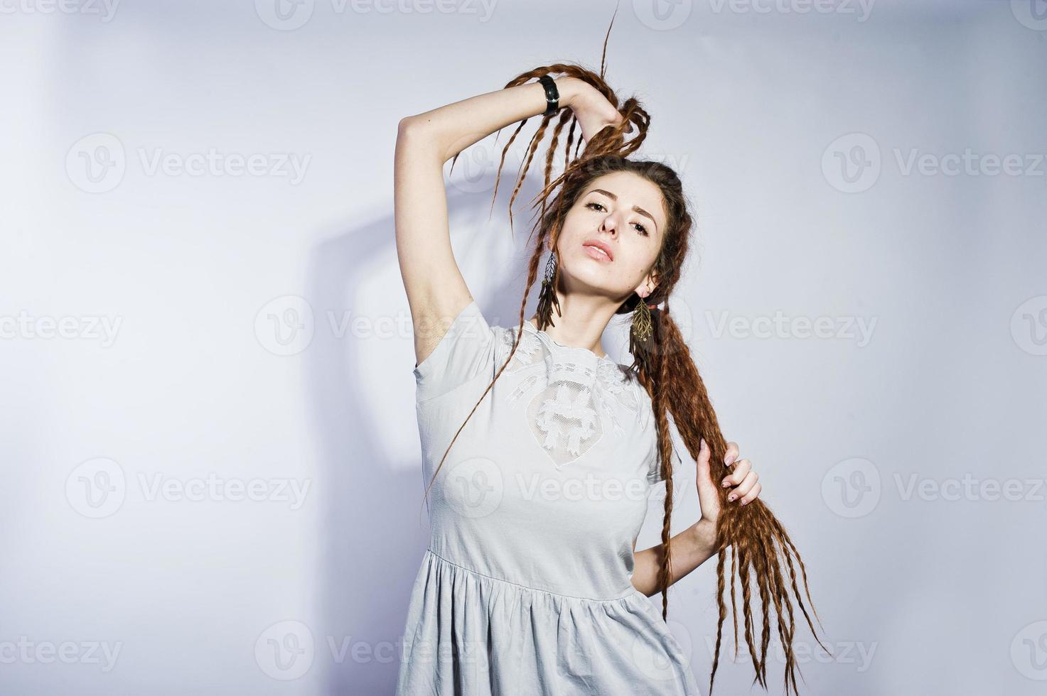 Studio-Shooting von Mädchen in grauem Kleid mit Dreads-Zöpfen auf weißem Hintergrund. foto