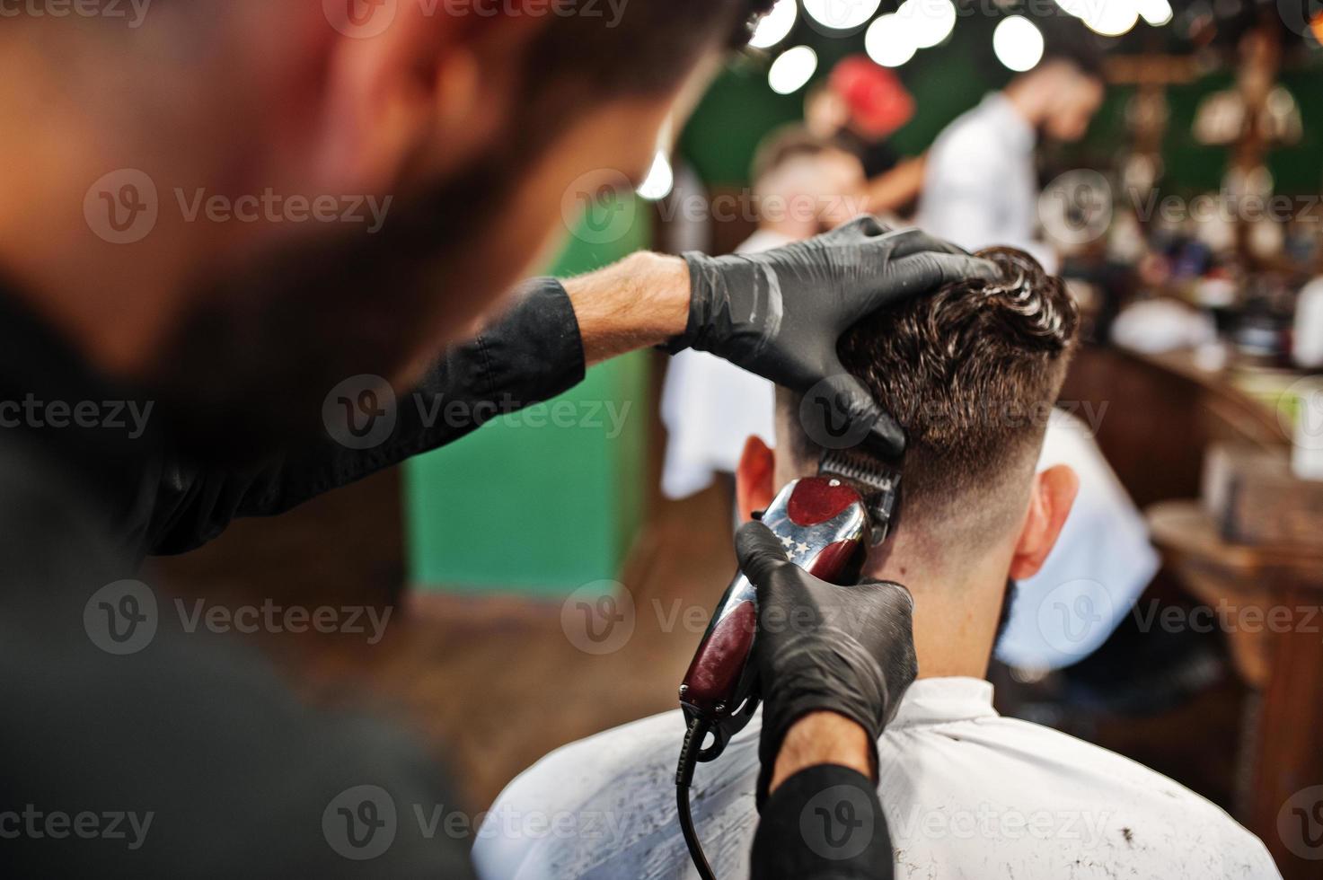 hübscher bärtiger mann im friseursalon, friseur bei der arbeit. foto