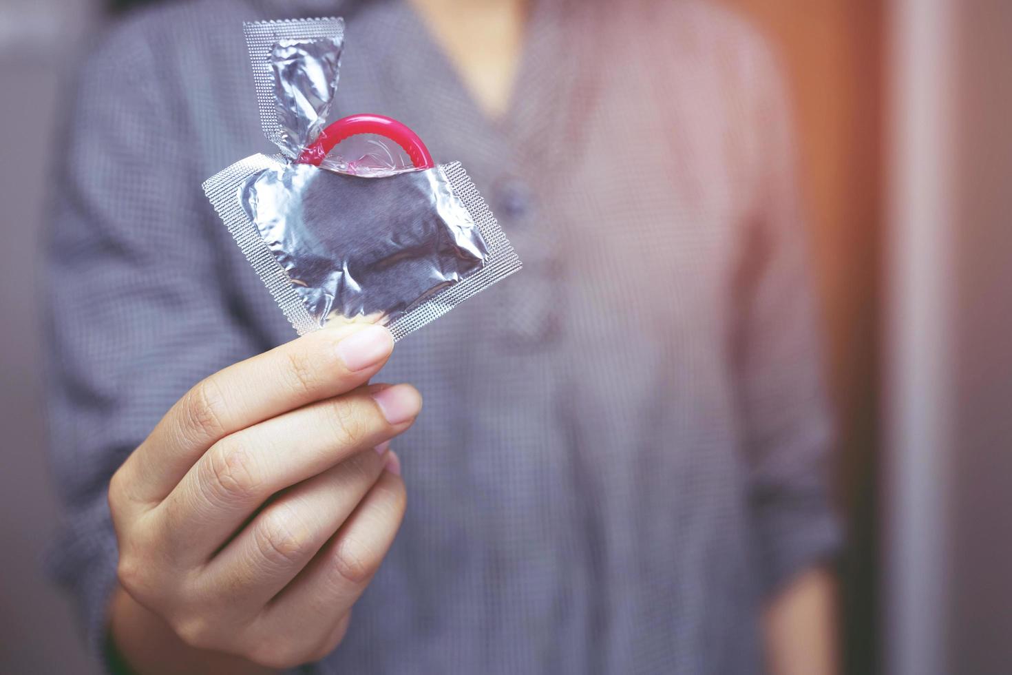 kondom gebrauchsfertig in weiblicher hand, geben kondom safer sex konzept auf dem bett verhindern infektionen und kontrazeptiva kontrollieren die geburtenrate oder sichere prophylaxe. Welt-AIDS-Tag foto