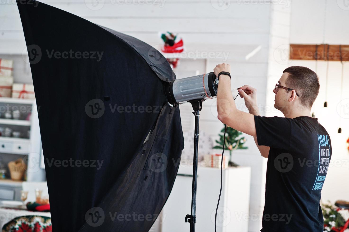 Der Fotograf passt das Blitzlicht im Studio an. foto