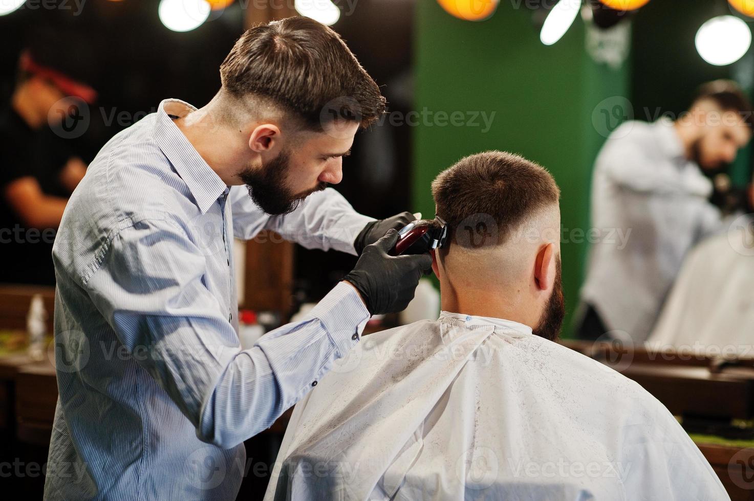 hübscher bärtiger mann im friseursalon, friseur bei der arbeit. foto