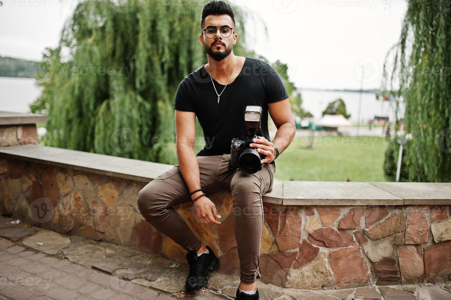 toller, schöner, großer arabischer bart-macho-mann-fotograf in brille und schwarzem t-shirt mit professioneller kamera in der hand. foto