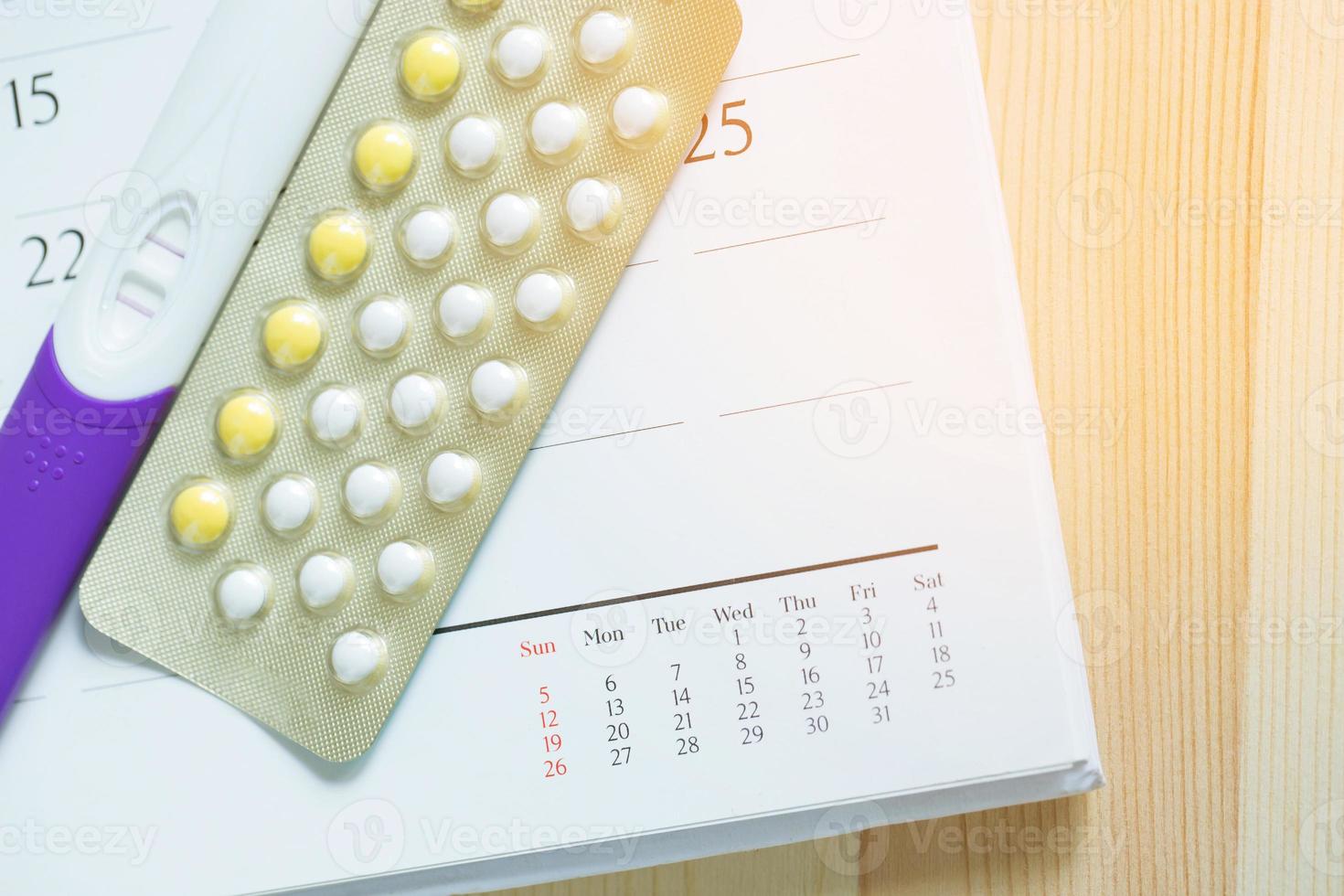 positiver Schwangerschaftstest und empfängnisverhütende Kontrollpillen am Datum des Kalenderhintergrunds. Konzept der Geburtenkontrolle im Gesundheitswesen und in der Medizin. foto