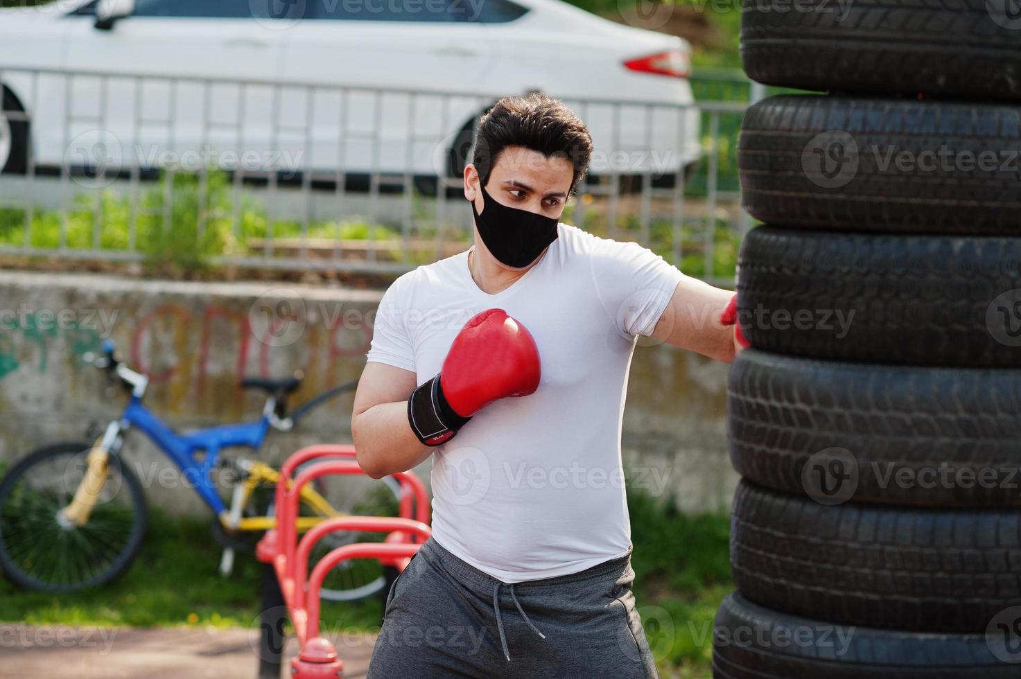 porträt trägt einen arabischen boxermann in schwarzer medizinischer gesichtsmaske, der während der coronavirus-quarantäne im freien boxt. foto