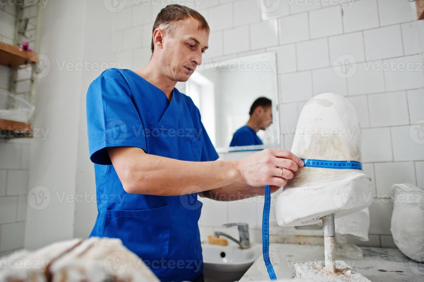 Prothesenmann, der während der Arbeit im Labor Beinprothesen herstellt, macht ein Modell aus Gips. foto