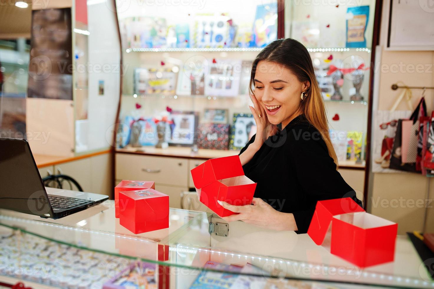 Porträt einer jungen kaukasischen Verkäuferin mit roten Geschenkboxen. kleines Geschäft mit Süßigkeiten-Souvenir-Shop. foto