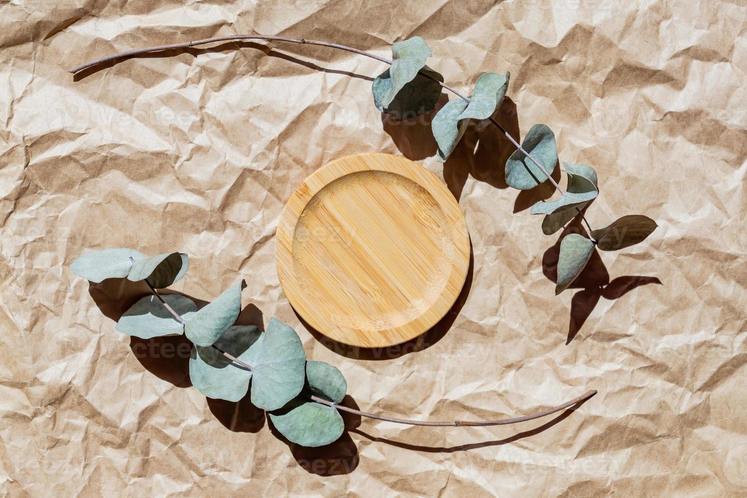 Holzplatte und Eukalyptuszweige auf Papierhandwerkshintergrund. mockup oe-vorlage für die produktpräsentation. Öko-Stil und Zero-Waste-Konzept foto