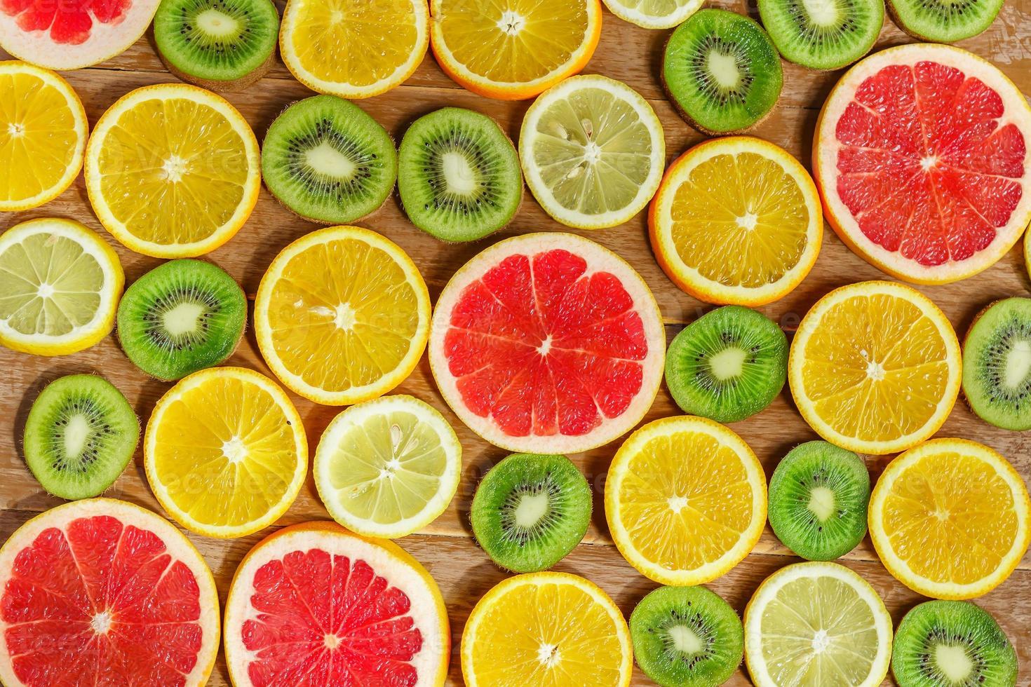 Rahmen mit Scheibe Orangen, Zitronen, Kiwi, Grapefruitmuster isoliert auf Holzhintergrund. flache Lage, Draufsicht foto
