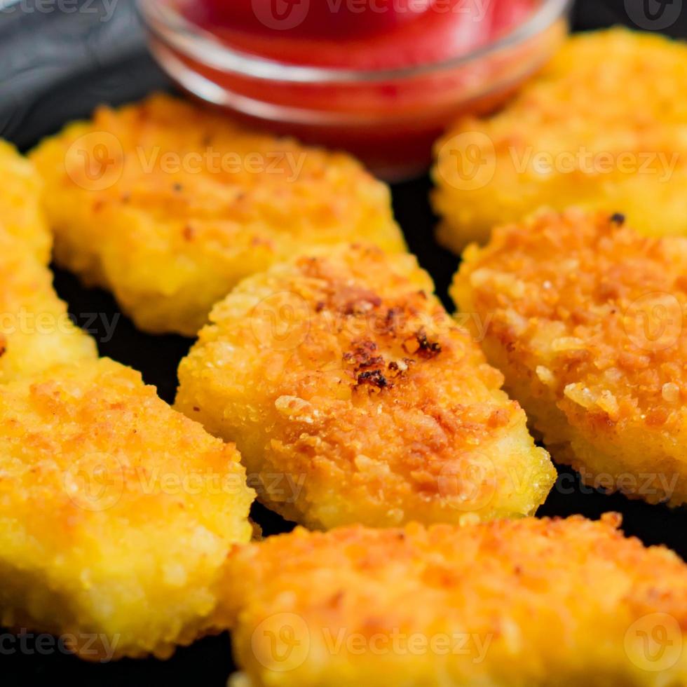 Gebratene knusprige Chicken Nuggets mit Ketchup auf schwarzem Teller. ungesundes Essen. foto