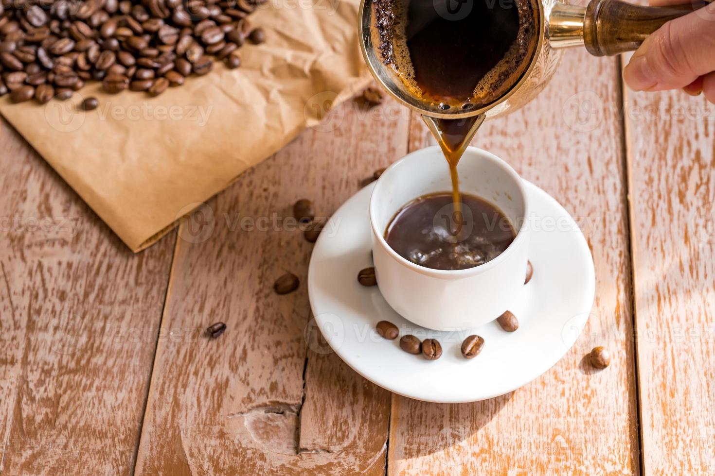 frisch gebrühter kaffee in cezve traditionelle türkische kaffeekanne frauenhand gießt kaffee in weiße tasse foto