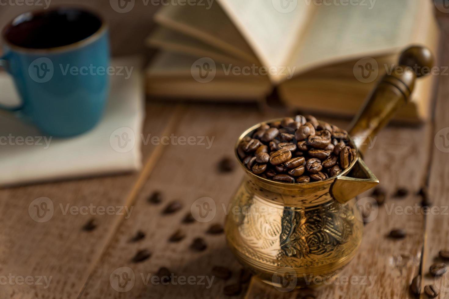 frisch geröstete kaffeebohnen in cezve traditionelle türkische kaffeekanne geöffnetes buch und tasse auf holztisch. foto