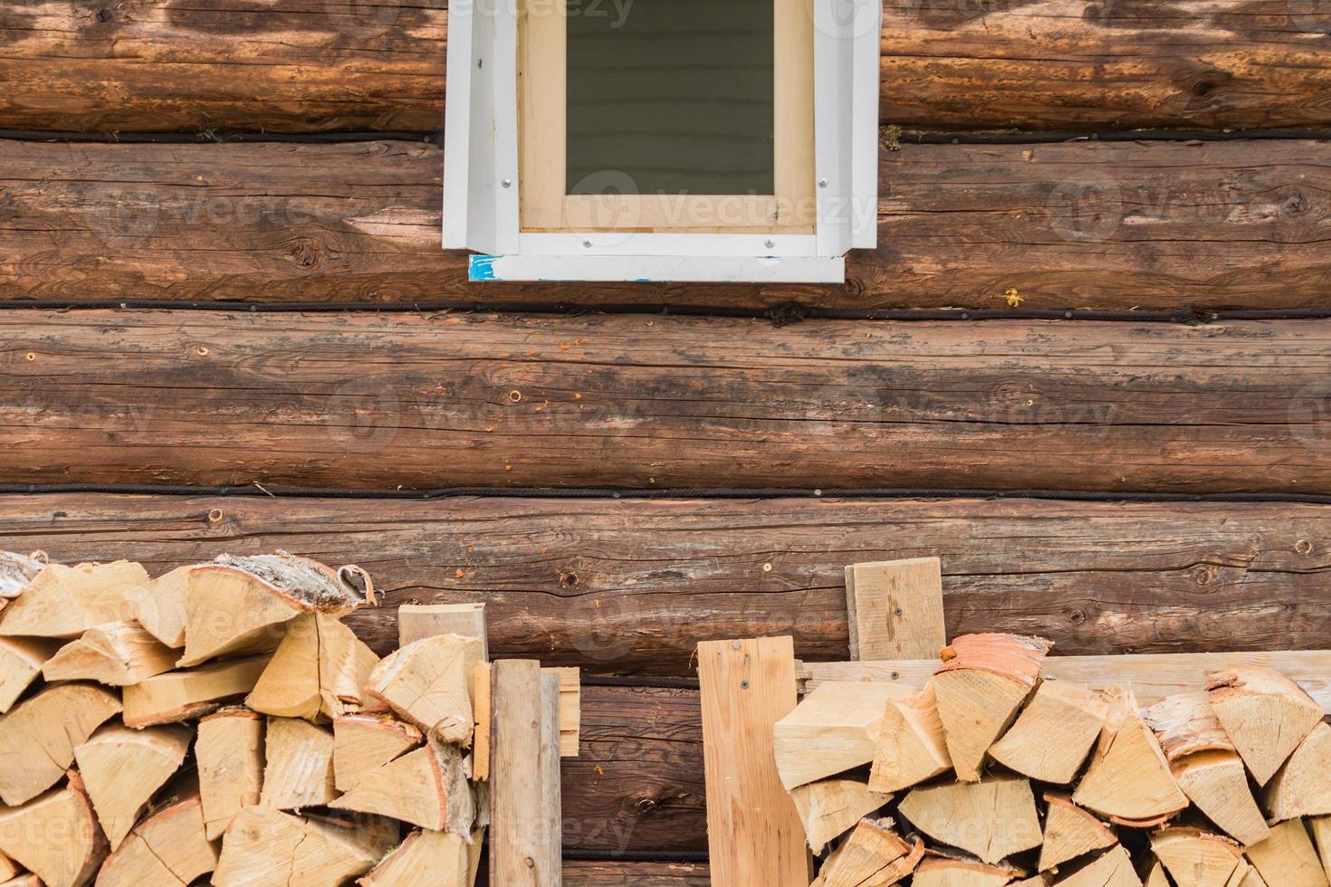 Zwei Stapel Brennholz in der Nähe der Blockwand unter dem Fenster. Außenlagerung von Holzstapeln foto