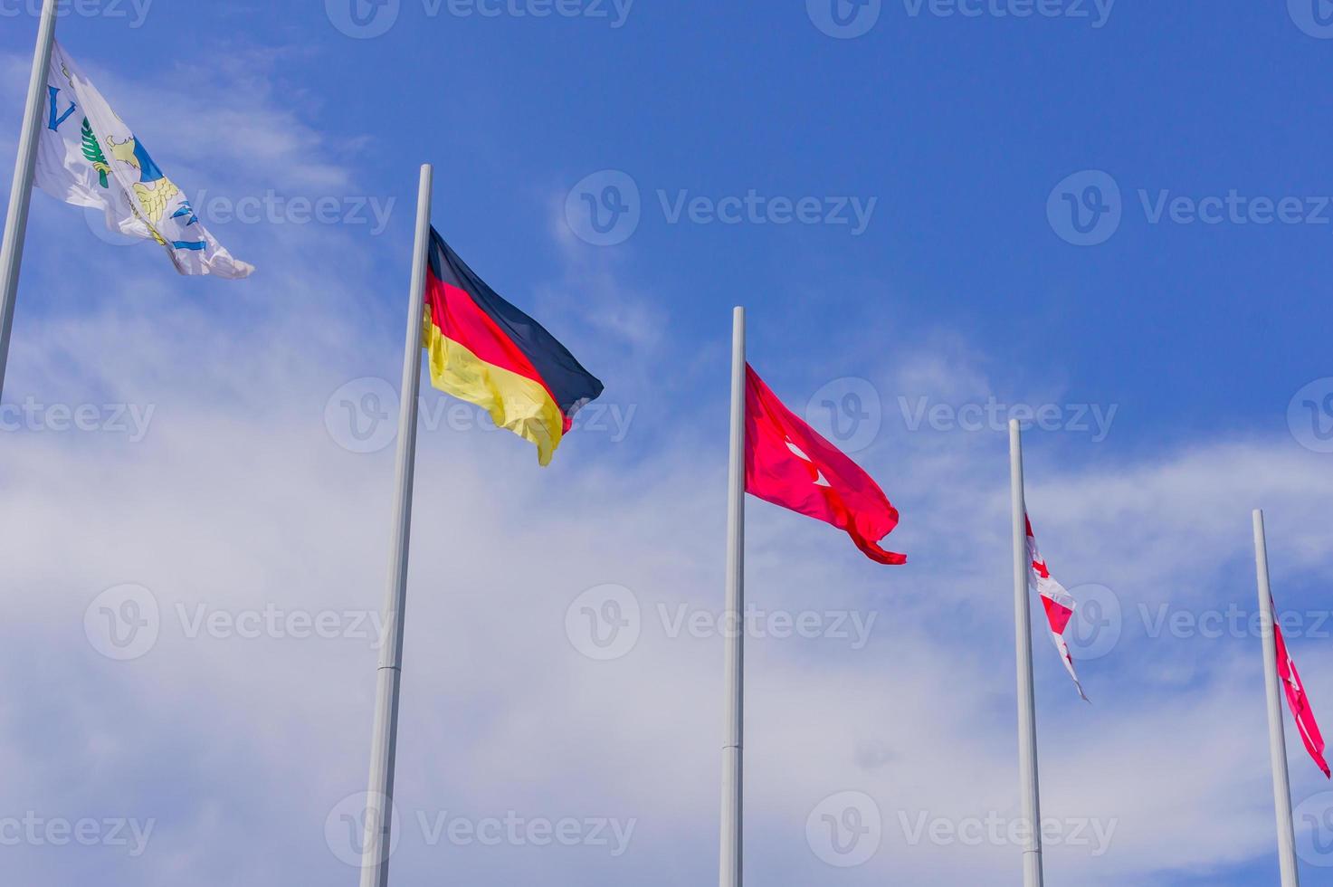 Bunte Flaggen aus verschiedenen Ländern wehen auf blauem Himmelshintergrund foto