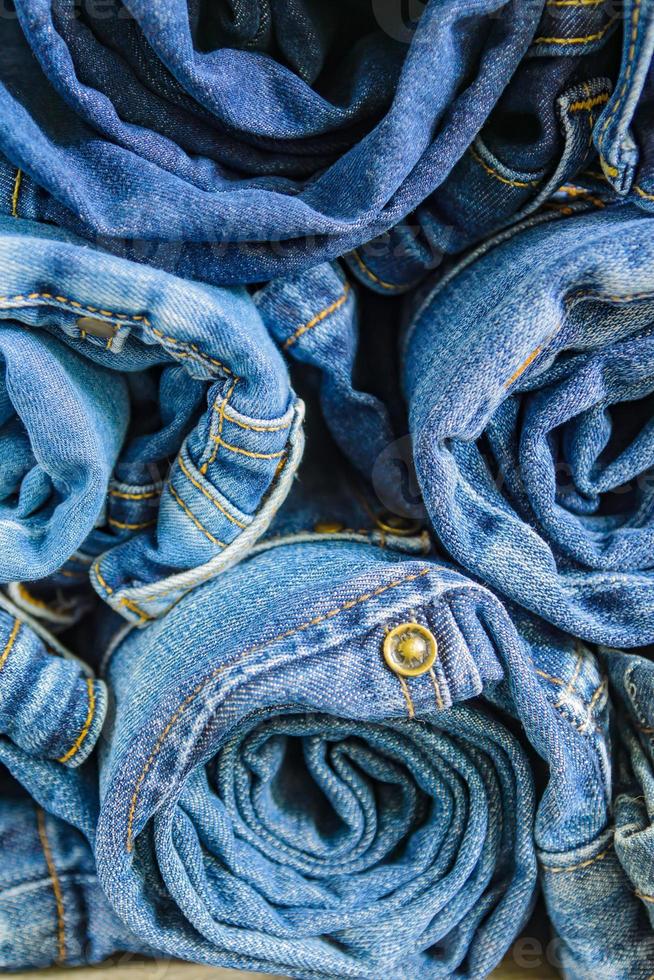 Rollen Sie blaue Denimjeans, die im Stapel angeordnet sind, Hintergrundtextur. Schönheits- und Modekleidungskonzept foto