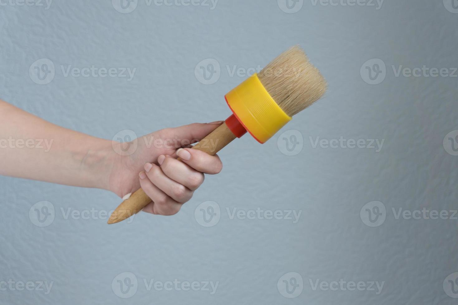 Frau, die einen großen Pinsel in der Hand hält, um Reparaturen durchzuführen. foto