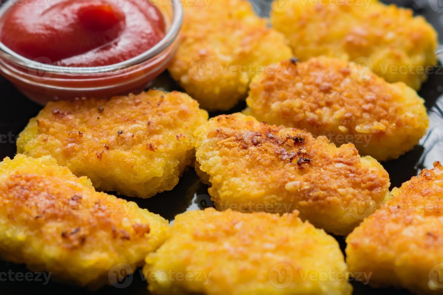 Gebratene knusprige Chicken Nuggets mit Ketchup auf schwarzem Teller. ungesundes Essen. foto