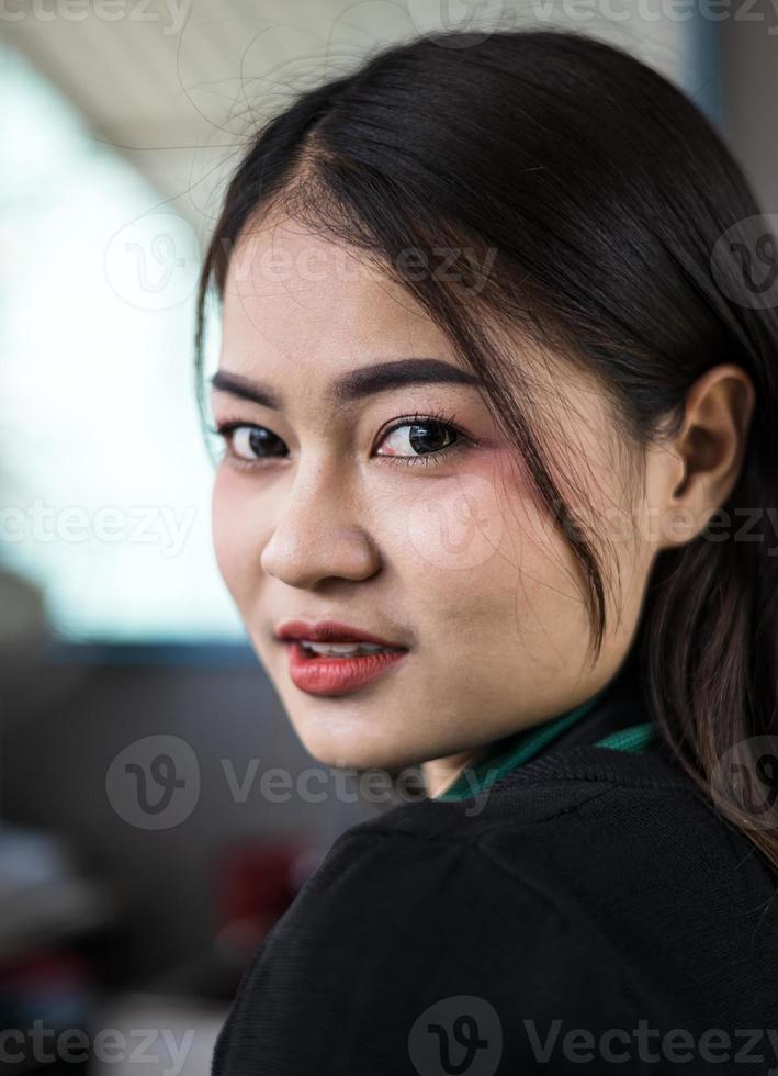 eine nahaufnahme eines porträts einer schönen thailändischen frau, die verführerisch in ihrem café lächelt. foto