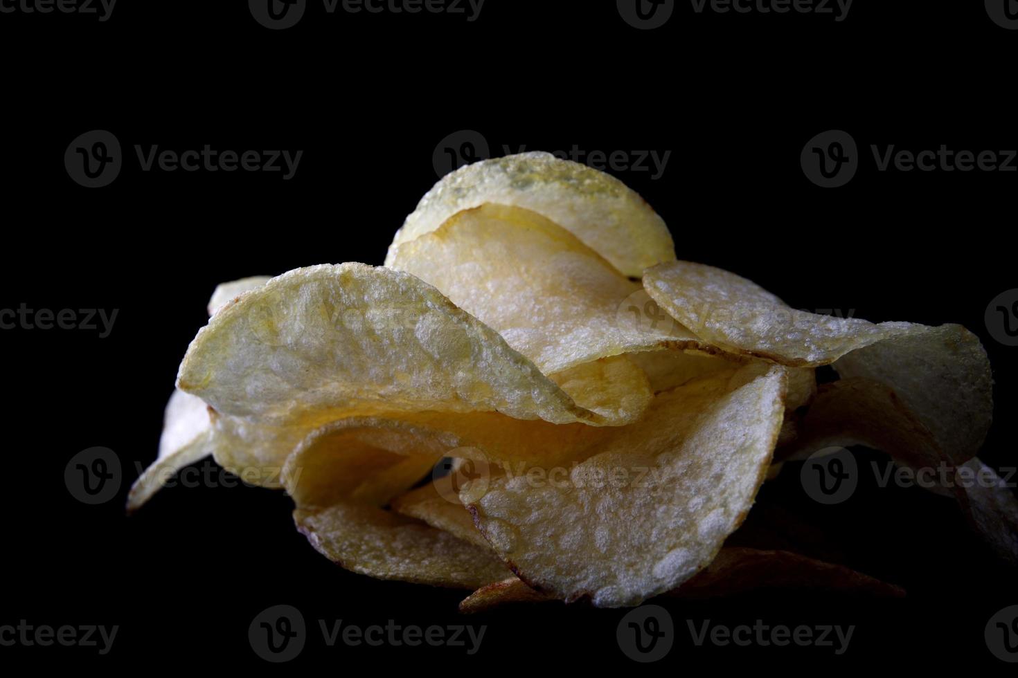 leckere Kartoffelchips sind auf schwarzem Hintergrund isoliert. foto