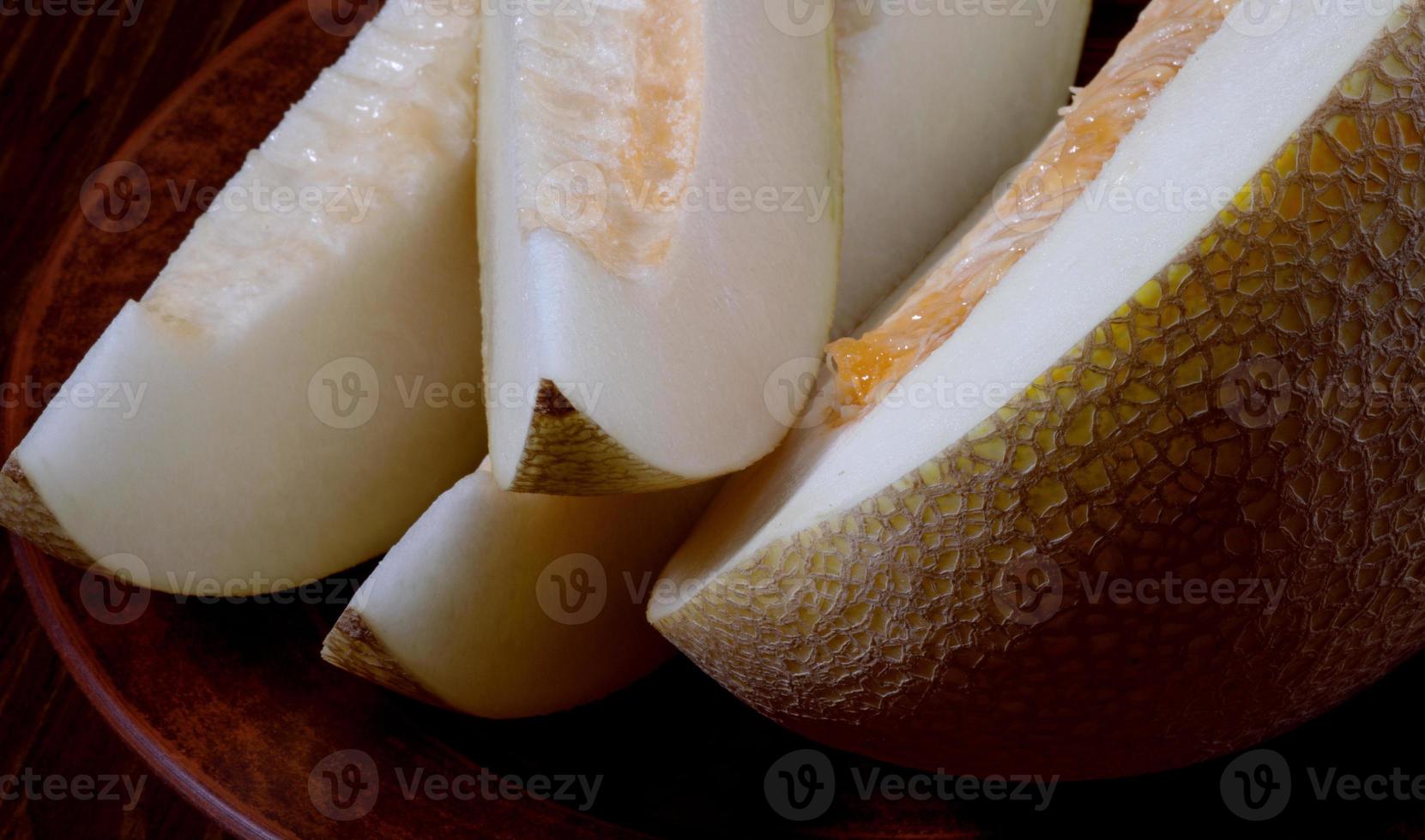 Scheiben reife Melone und halbe Melone auf einer Tonplatte. foto