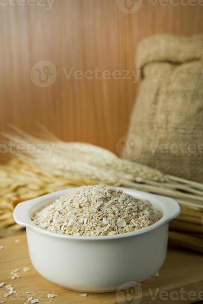 die gesunden Haferflocken aus Frühstücksflocken in Schüssel auf Holztisch. foto