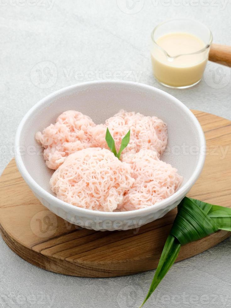 Kue Putu Mayang ist ein traditioneller indonesischer Snack aus zu einer Kugel zusammengerollten Reismehlsträngen, serviert mit Kokosmilch und Palmzucker. foto