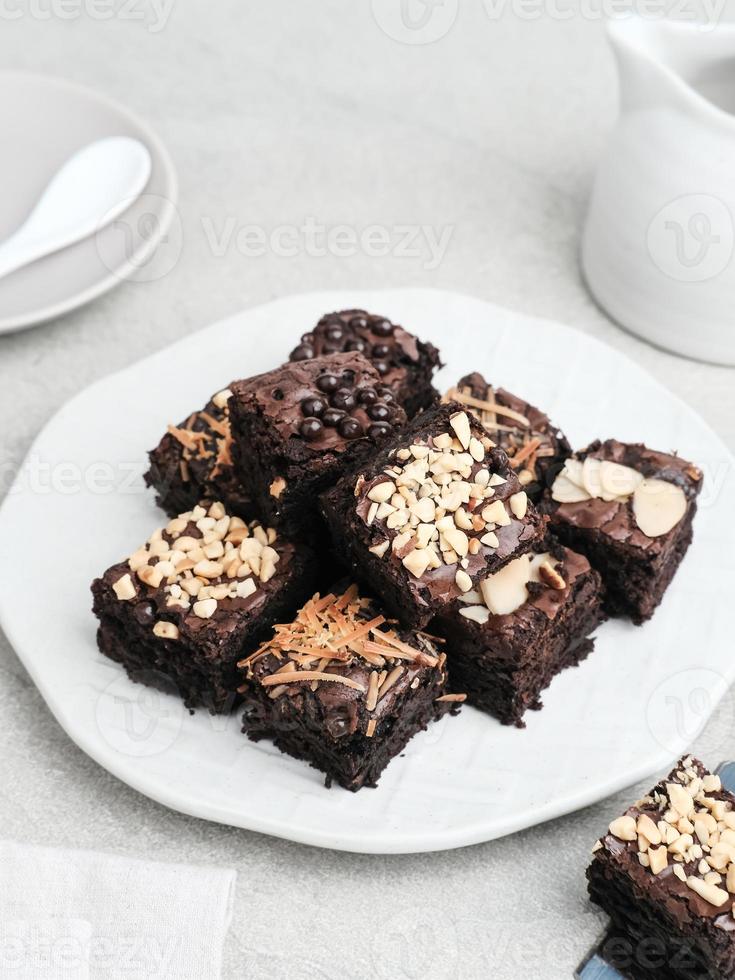 hausgemachte Schokoladen-Fudge-Brownie mit Mix-Topping, Nahaufnahme, serviert auf Teller, isoliert auf weißem Hintergrund. Bild mit selektivem Fokus. foto