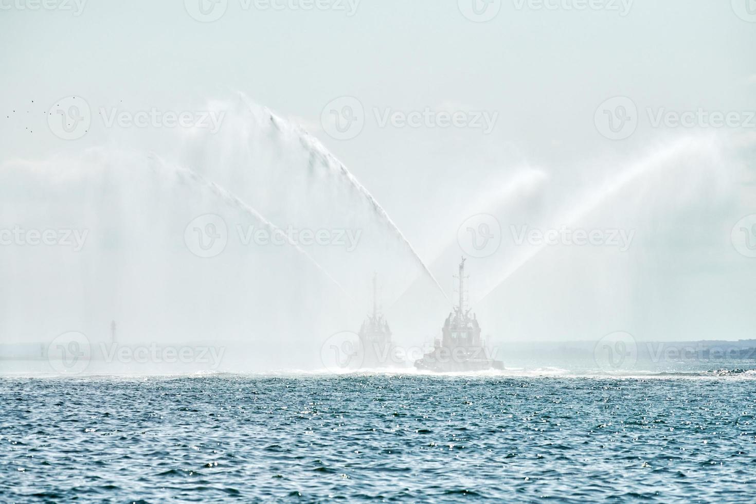 Schlepper, die Wasserstrahlen sprühen, Wasserwerfer zur Brandbekämpfung demonstrieren, Löschboote, die Schaum sprühen foto