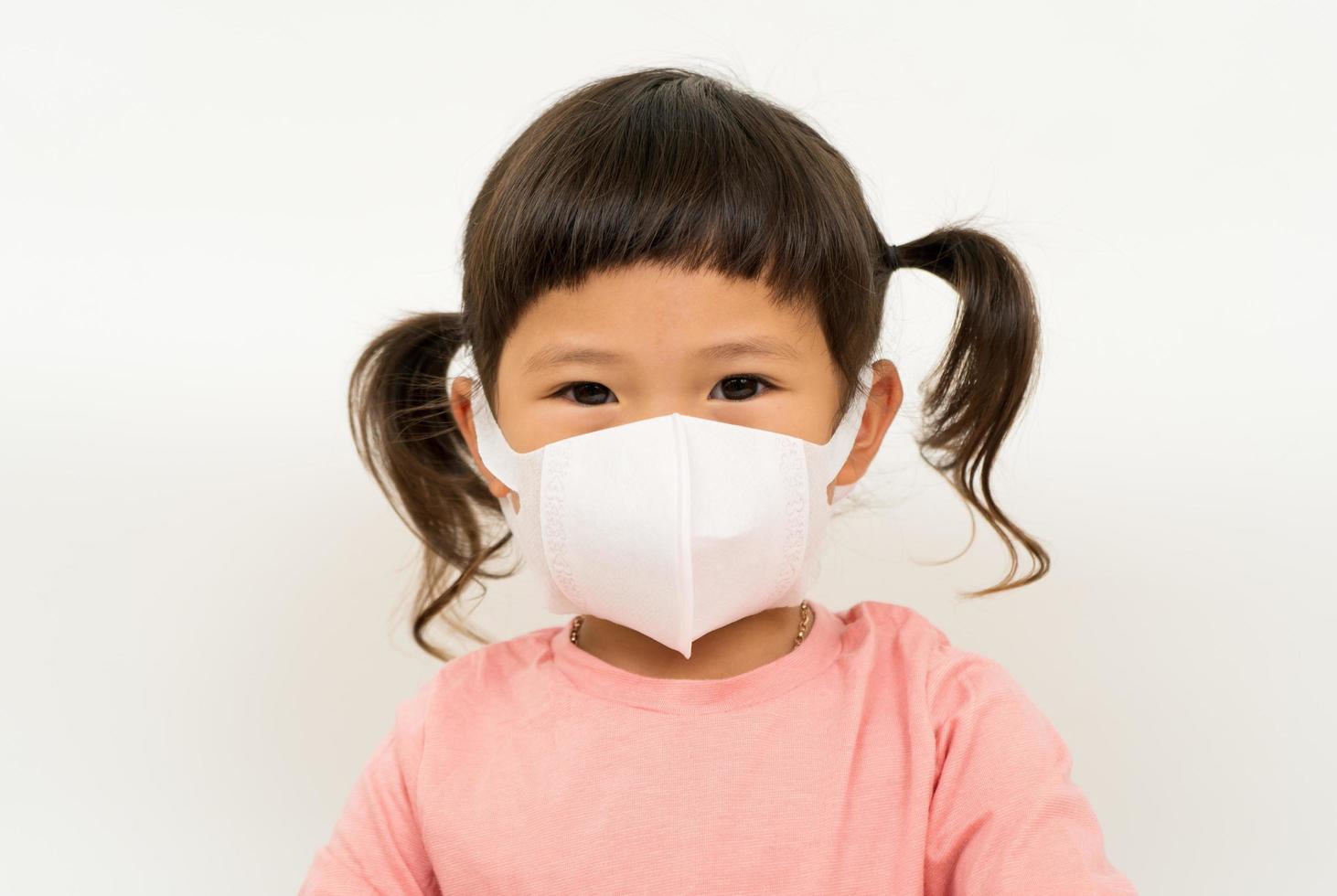 kleines asiatisches mädchen mit maske zum schutz des pm2.5- und coronavirus-konzepts foto