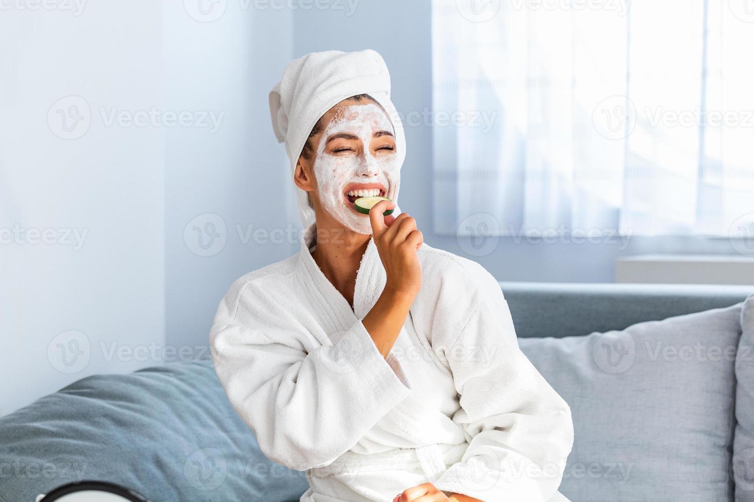 Schöne junge Frau mit Gesichtsmaske auf ihrem Gesicht, die frische Gurkenscheiben hält. hautpflege und behandlung, spa, natürliche schönheit und kosmetikkonzept foto