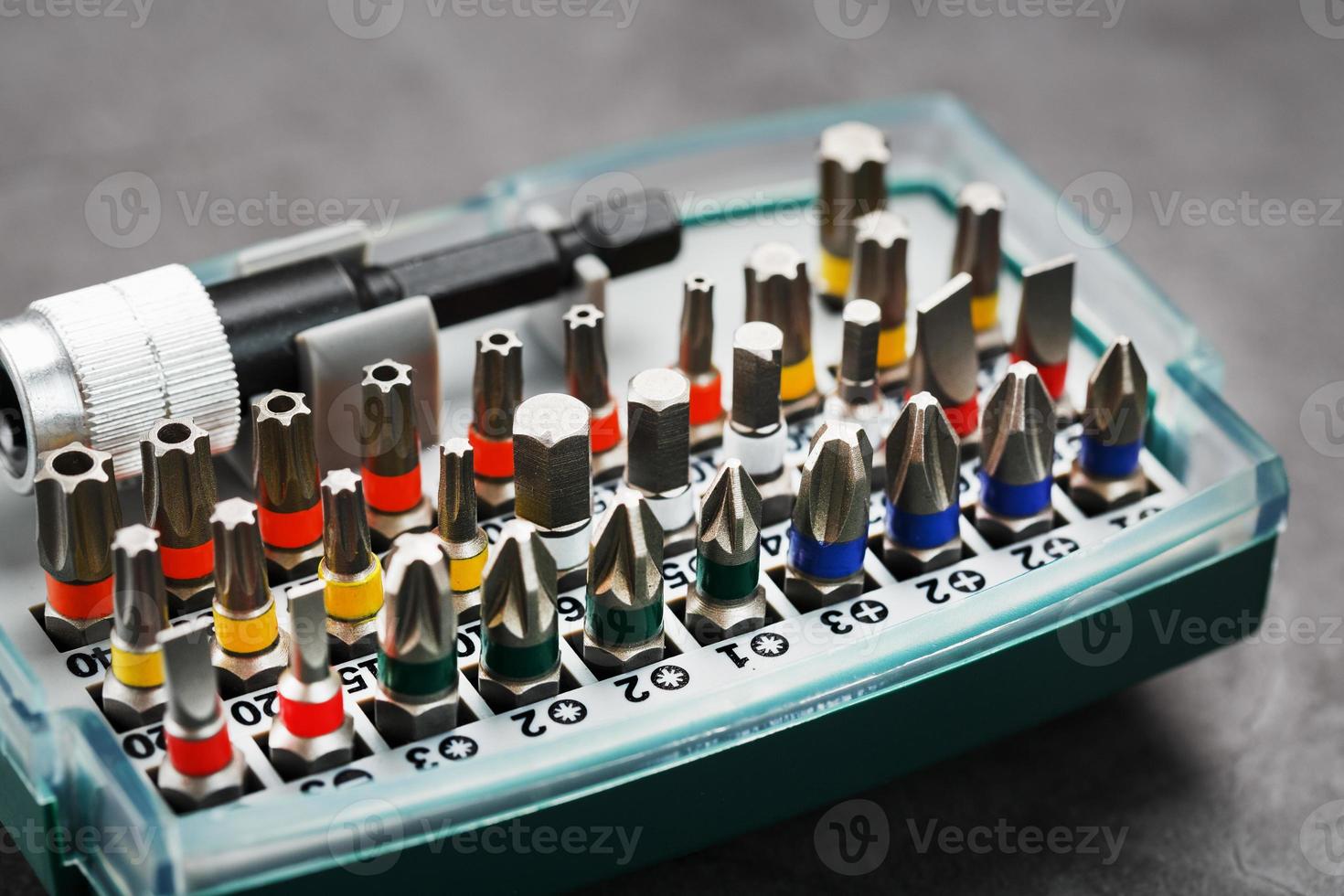 Eine Reihe verschiedener Bits für Schraubendreher und Reparaturen in einer Box auf grauem Hintergrund foto